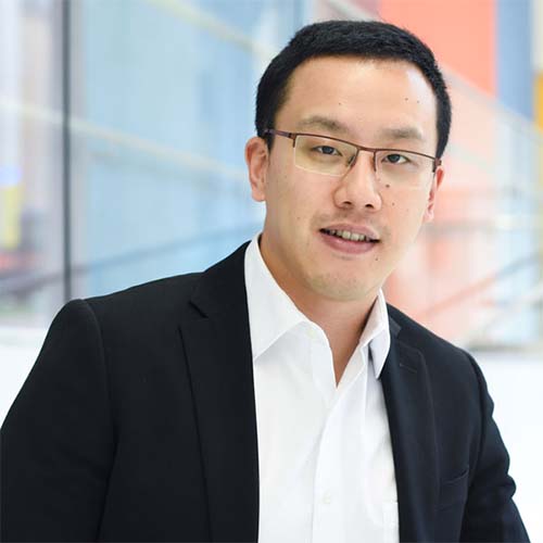 A headshot of CS assistant professor Xuesu Xiao wearing a white collared shirt and black suit jacket.