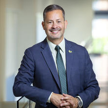 George Mason's Provost Antony wearing a blue suit and green tie.
